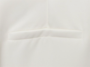Detailed view of the welt pocket and premium fabric texture on an ivory white blazer