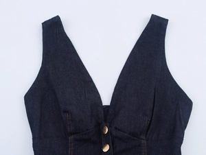 Détail du gilet en jean bleu foncé avec décolleté en V et boutons en cuivre vintage