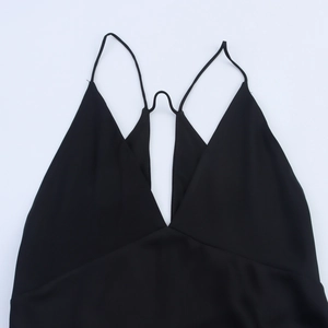 Elegante zwarte jurk met diepe V-hals, smalle bandjes en een strak minimalistisch