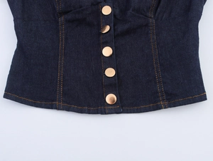Détail du haut en jean bleu foncé avec coutures contrastées et boutons dorés