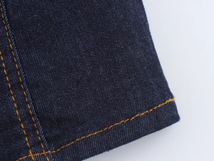 Gros plan détaillé sur la texture du denim bleu foncé avec coutures orange contrastées