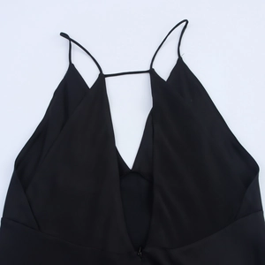 Detailopname van een zwarte zijdeachtige slipdress met diepe V-hals en dunne bandjes