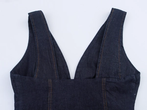 Détail de gilet en jean bleu foncé avec col en V et coutures orange contrastées