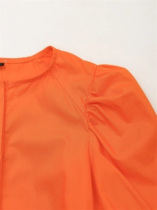 Detalle de vestido naranja con mangas abullonadas plisadas y textura de tela de algodón