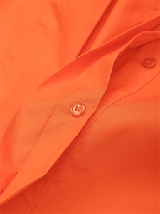 Primer plano de la tela naranja del vestido con botones de resina y costuras precisas