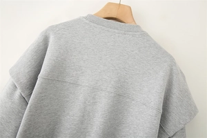 Detail eines grauen Sweatshirts mit Rundhalsausschnitt und Rippkragen auf Holzkleiderbügel