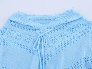Détail d'un pull en maille ajourée bleu clair avec motifs de losanges et liens au col