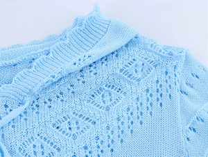 Détail de la maille ajourée bleu clair avec motifs pointelle et col à bords ondulés