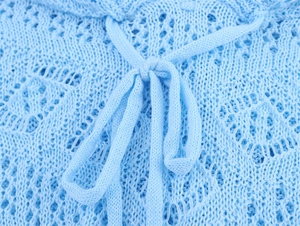 Détail de tricot ajouré bleu ciel avec nœud de serrage et motifs floraux au crochet