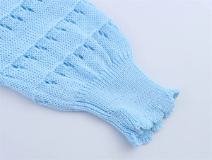Détail du pull en maille ajourée bleu clair avec poignets à volants et motifs pointelle