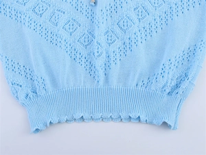Détail d'un pull en maille ajourée bleu clair avec motifs losanges et ourlet volanté