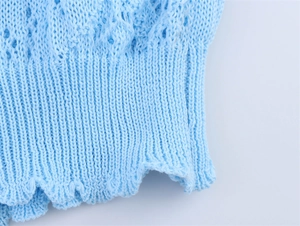 Détail du pull en maille ajourée bleu ciel montrant les poignets côtelés et la texture