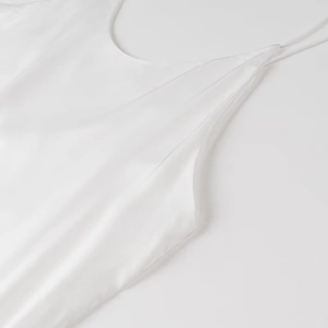 Detailed view of dual spaghetti straps and smooth white satin fabric on dress neckline