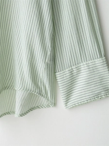 Detail of light green striped shirt hem and cuff with precision stitching and soft fabric