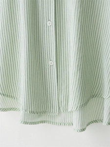 Close-up of light green striped shirt with white buttons and curved hem detail