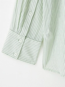 Detail of light green striped long sleeve shirt showing white buttons and cuff texture