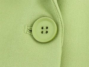 Makroaufnahme von passendem Knopf und Knopfloch an einem grünen Blazer aus Twill