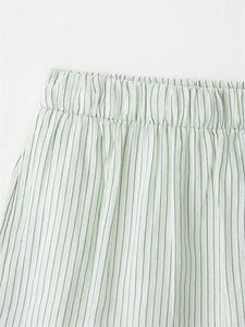 Detail of light green striped shorts with elastic waistband and soft cotton linen texture