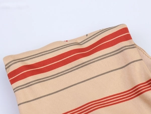 Close-up of beige ribbed dress fabric with red and grey stripes and soft texture