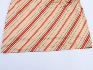 Close-up of khaki and red striped fabric with side drawstring gathering and hem stitching