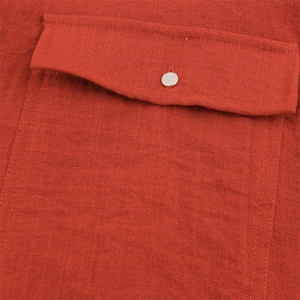 Detail von ziegelrotem Baumwoll-Leinen-Stoff mit Tasche und silbernem Metallknopf
