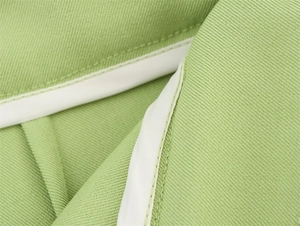 Detail von hellgrünem Twill-Stoff mit weißer Paspelierung und sauberer Nahtführung