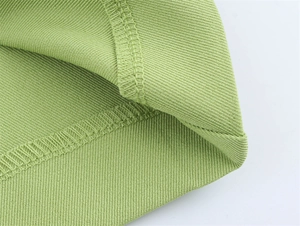 Detailaufnahme von hellgrünem Twill-Gewebe mit professioneller Overlock-Stich-Verarbeitung