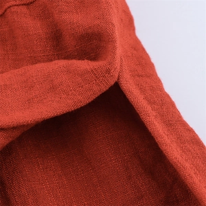 Detailaufnahme des Seitenschlitzes und der Baumwoll-Leinen-Textur der ziegelroten Hose