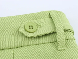 Detail der grünen Twill-Anzughose mit Stoffstruktur und Knopfleiste am Bund
