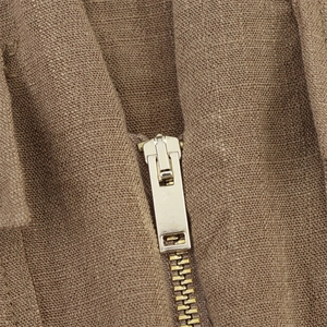 Detail aus braunem Leinenstoff mit hochwertigem hellgoldenen Metallreißverschluss