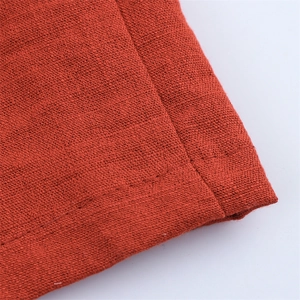 Nahaufnahme der orangefarbenen Baumwoll-Leinen-Textur und feinen Nähten am Safari-Set