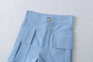 Detail of light blue high waist shorts with cargo pockets and silver button closure