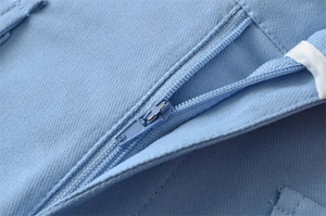 Macro shot of smooth zipper and twill fabric texture on high-waist cargo shorts