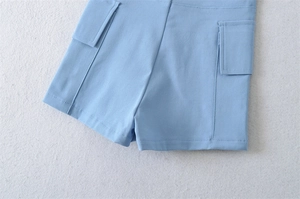 Detail view of high-waisted cargo shorts in light blue with side flap pockets