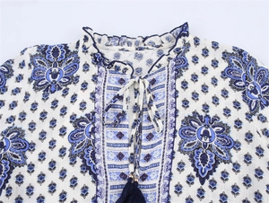 Détail de motif paisley bleu et blanc avec col à volants et pompons décoratifs