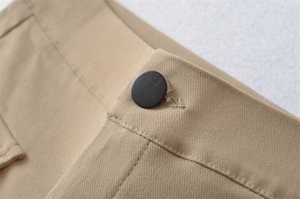 Detailed macro view of khaki cotton twill fabric with black matte button and stitching