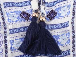 Détail de glands bleu marine avec perles dorées sur tissu en coton et lin à imprimé floral