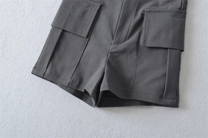 Detail of dark grey utility shorts showing large flap pockets and premium stitching