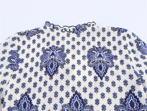 Détail du col montant à volants et imprimé ethnique bleu sur robe en lin blanc