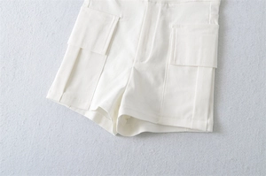 Macro shot of high-waist white cargo shorts with large flap pockets and fine stitching