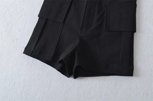 Detail view of black high-waisted cargo shorts with large flap pockets and stitching