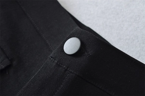 Detailed macro view of the black matte button and stitching on woven retro shorts