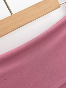 Dettaglio della trama in maglia rosa con cuciture fini su gruccia di legno