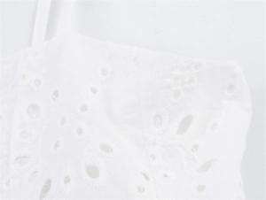 Detailopname van het bloemige broderie-borduurwerk op een witte bohemian mouwloze top