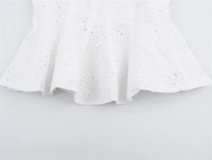 Detailweergave van wit broderie anglaise op de ruches peplum zoom met bloemmotieven
