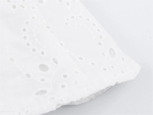 Detail van witte katoenen stof met prachtig broderie anglaise en golvende randen