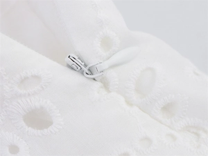 Detail macro-opname van een onzichtbare rits op een witte geborduurde katoenen blouse