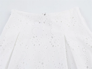 Detail van witte katoenen blouse met bloemenborduursel en geplooide taille-accenten