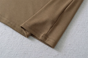 Detail of tan knit fabric showing fine texture and professional double-needle stitching