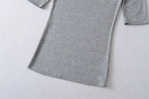 Close-up of light grey slim fit top showing double-needle stitched hem and knit texture